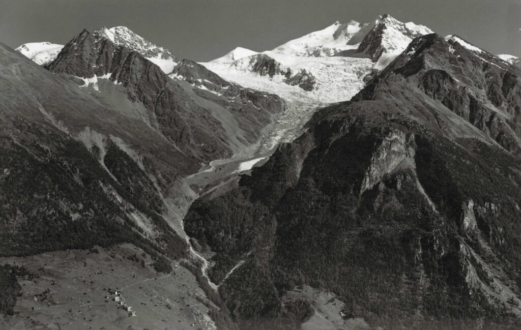 Het dorp Gasenried met de Riedgletscher en Nadelgrat in ca 1950. Fotograaf: Emanuel Gyger, collectie ETH Zürich foto hs_1458-gk-b017-0000-0001.