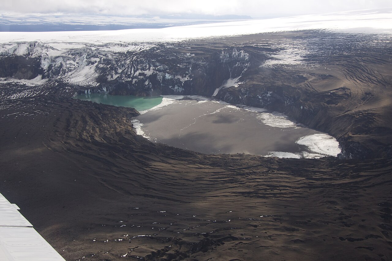 De vulkaanuitbarsting van 2011 was groot genoeg om de honderden meters dikke laag ijs boven het Grímsvötn te doen smelten. Het ijs ziet zwart van de tefra. Bron: wikipedia.