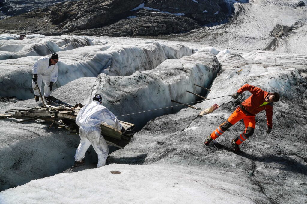 Vliegtuigbrokken zijn uit de gletsjer gesmolten en worden in 2018 door het Zwitserse leger afgevoerd. Fotograaf: Stefan Meienhofer.
