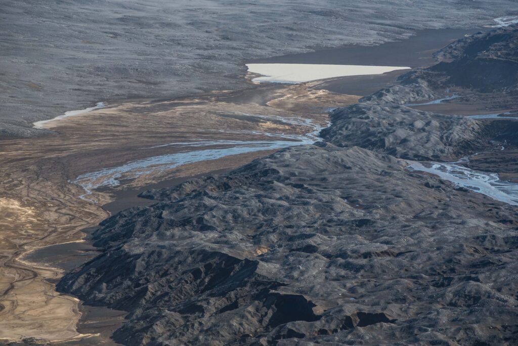 Smeltwater waaiert uit achter de morene van de (oostelijke) Dyngjujökull en zakt de zandige bodem in.