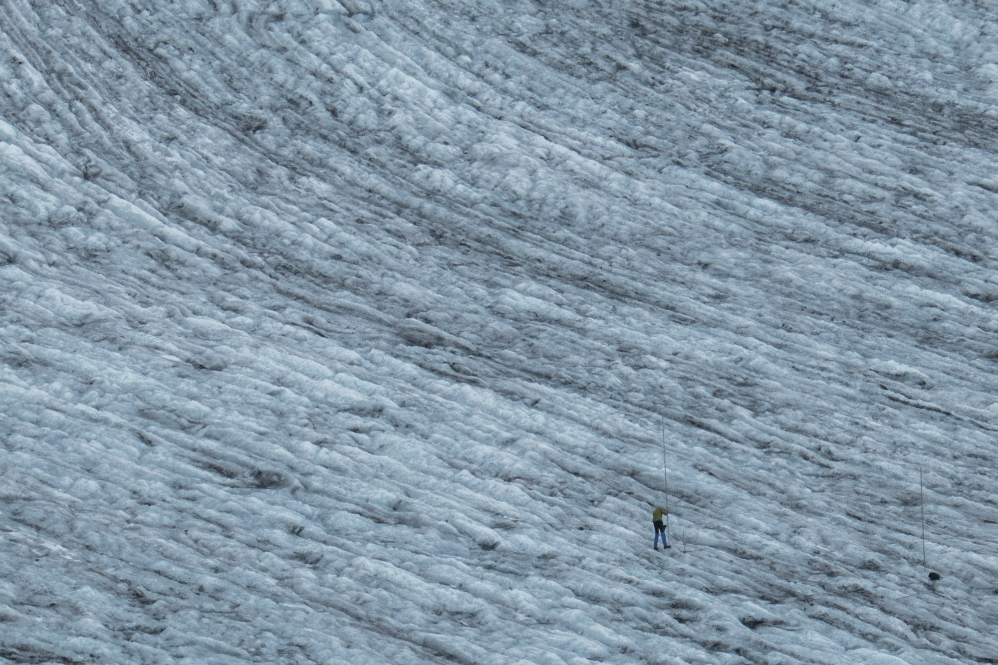 Iemand plaatst meetpalen op de Silvrettagletscher.