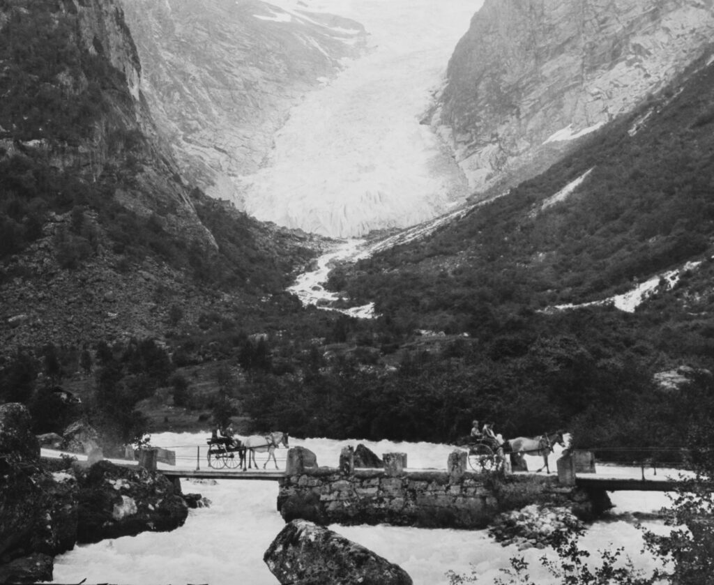 Carriages cross the bridge in front of Melkevollbreen, circa 1900-1920. Source: Nasonalbiblioteket.