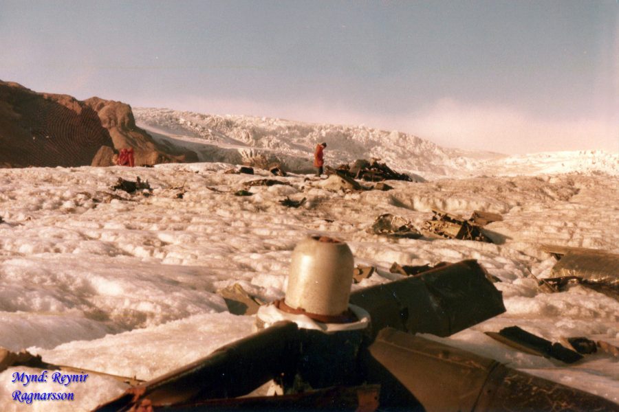 Brokstukken van het vliegtuig liggen op het ijs, met een propeller op de voorgrond. Fotograaf: Reynir Ragnarsson, 1981.